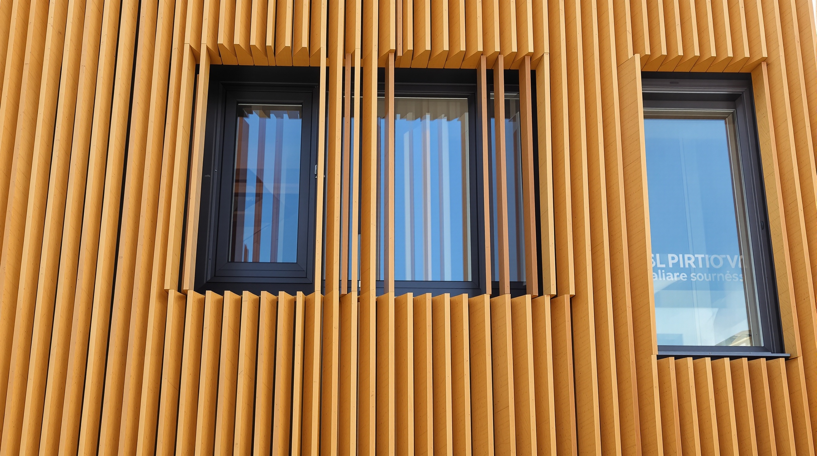 Façade contemporaine en bardage bois claire-voie avec lames espacées et fond pare-pluie noir visible