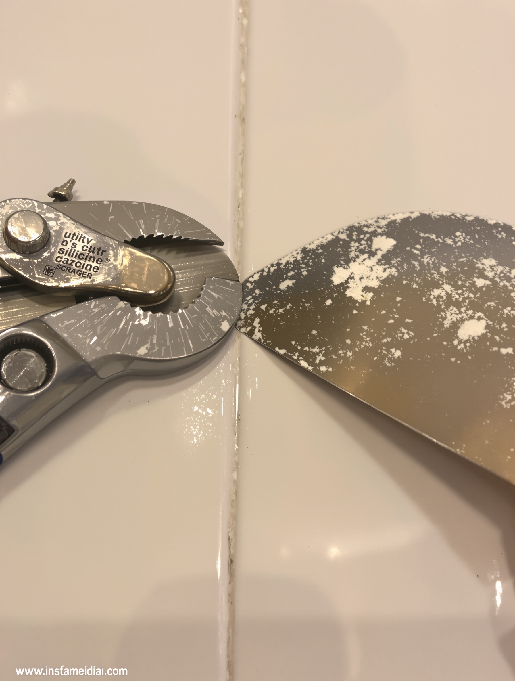 Gros plan sur un cutter et un grattoir d'angle utilisés pour retirer du mastic silicone récalcitrant sur un support carrelé