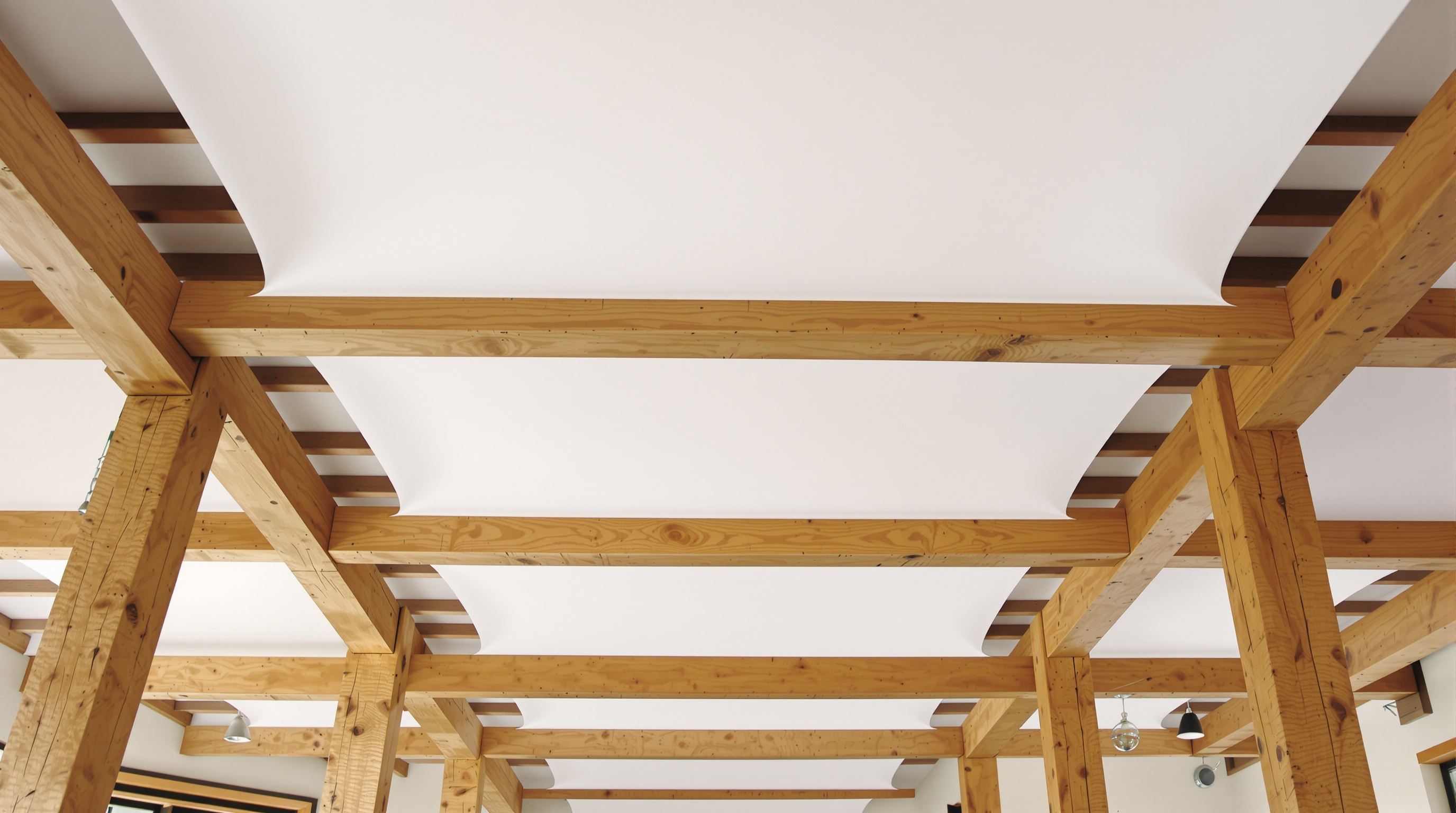 Plafond tendu contemporain installé entre poutres apparentes bois – rendu lisse moderne contrastant harmonieusement avec le bois.